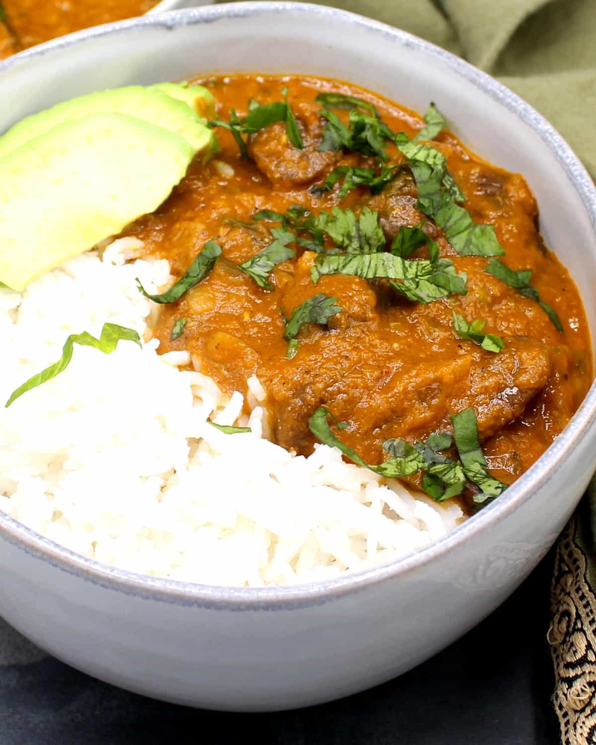 Chestnut xacuti in bowl with rice and avocado.