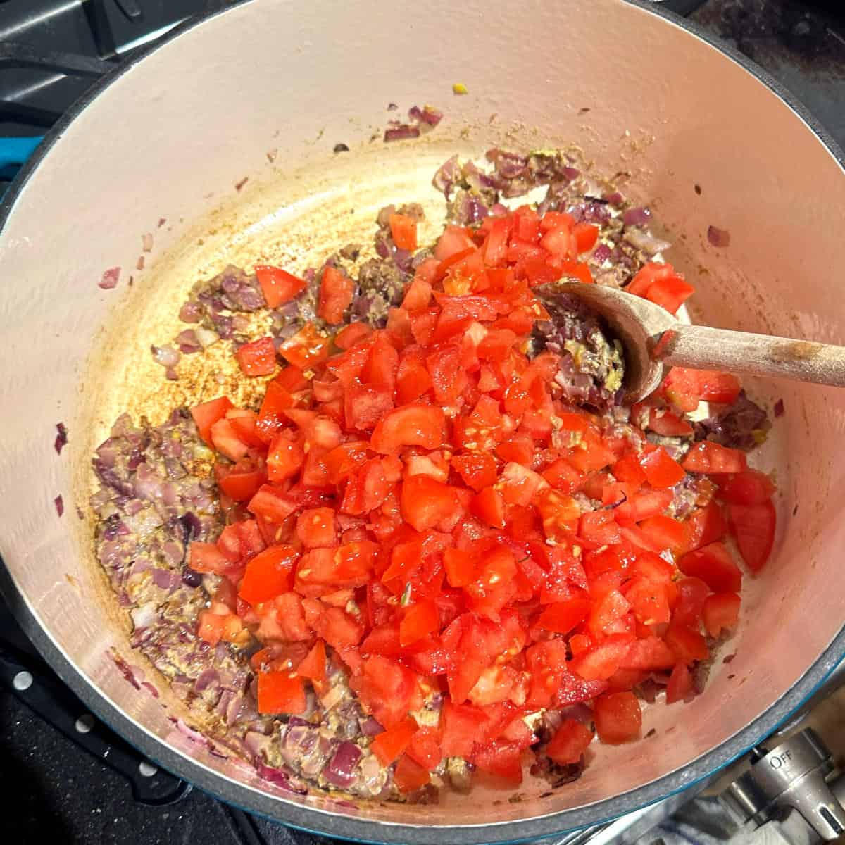 Tomatoes added to pot with onions.