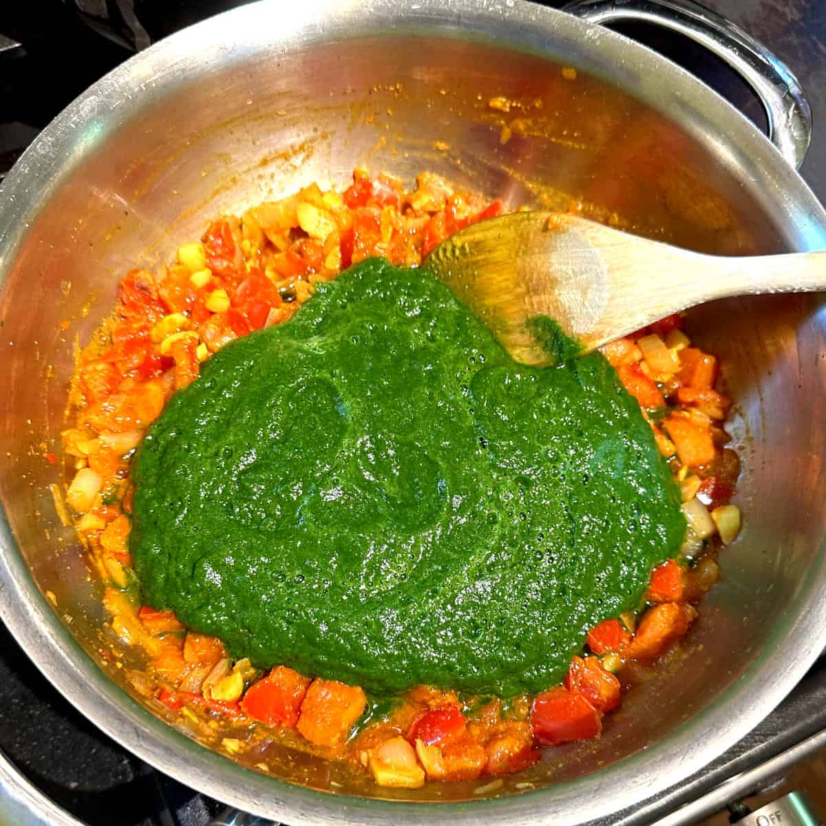 Swiss chard puree added to pot with spices, onions and tomatoes.