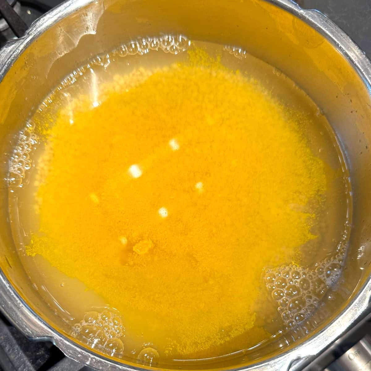 Moong dal with turmeric in water in pressure pan.