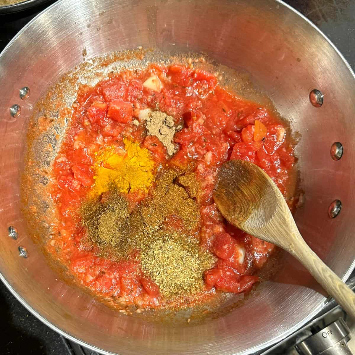 Tomatoes with spices in pot.