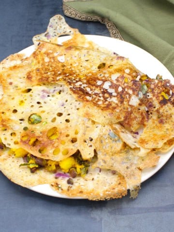 Two rava dosas on a plate with potato stuffing.