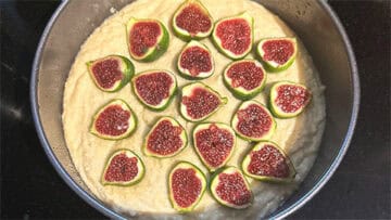 Batter in springform pan with halved figs arranged on top.