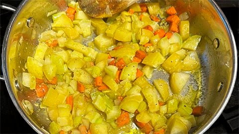 Onions, garlic, squash and carrots sauteing in pan.