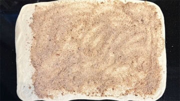 Cinnamon sugar spread over the rolled dough.