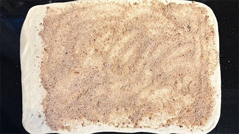 Cinnamon sugar spread over the rolled dough.