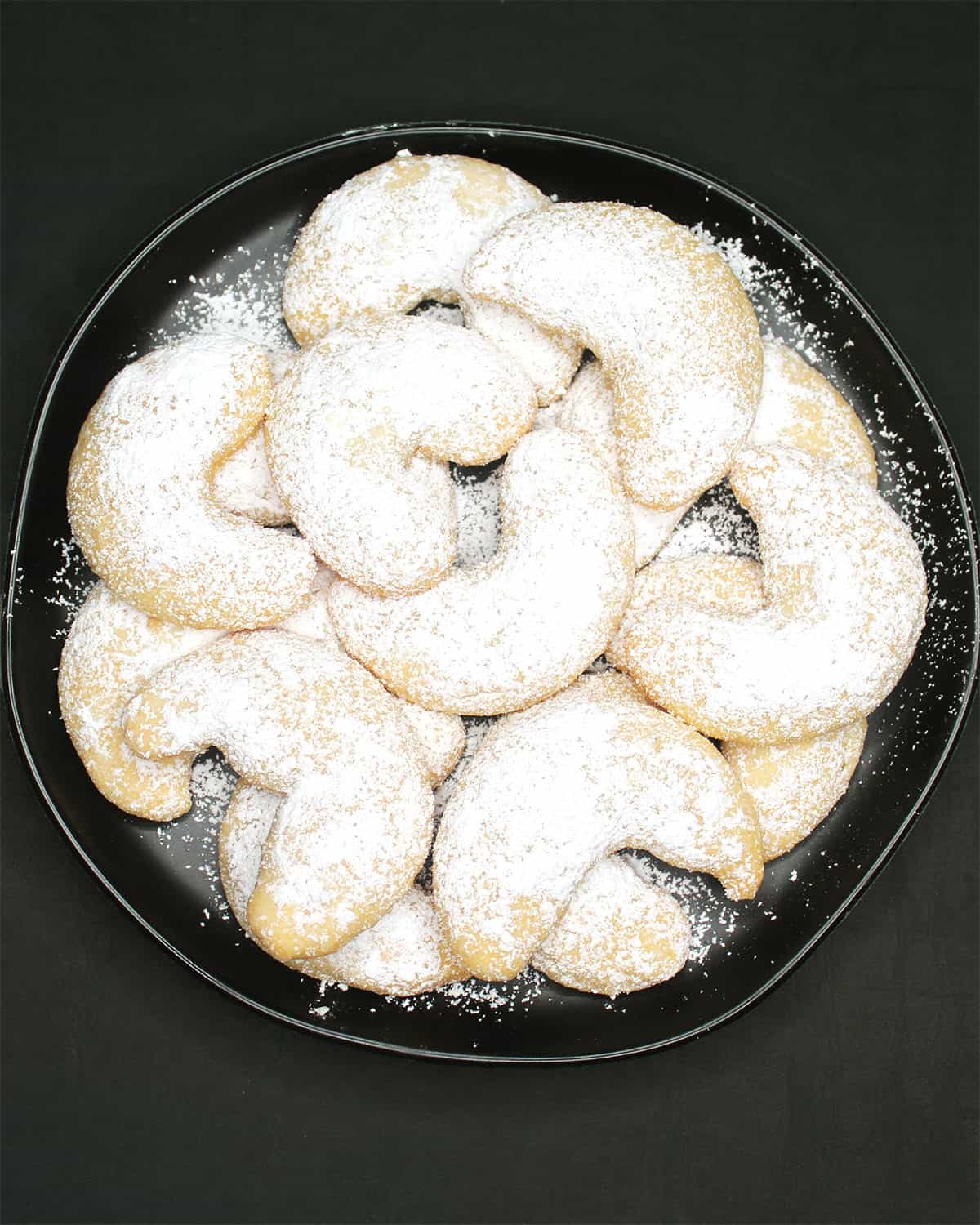 Vegan vanillekipferl cookies in a black plate.