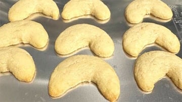 Baked vanillekipferl cookies on baking sheet.