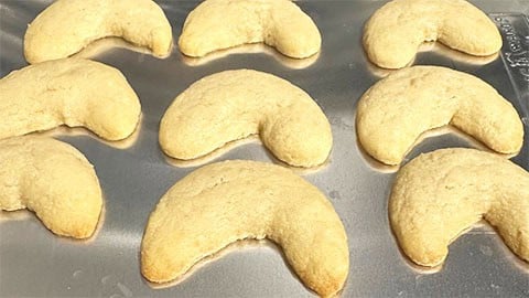 Baked vanillekipferl cookies on baking sheet.
