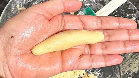 Cylinder of vegan vanillekipferl cookie on hand.