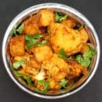 Top down view of aloo gobi in copper and steel bowl.