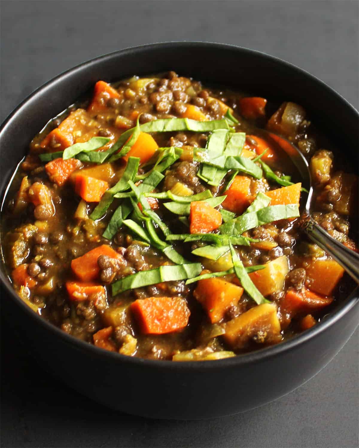 Front view of dal soup with beluga lentils in black bowl.