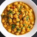 Close-up shot of chickpea curry in a white bowl.