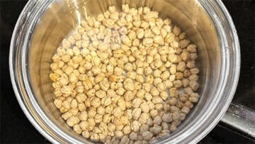 Dried chickpeas with water in saucepan.