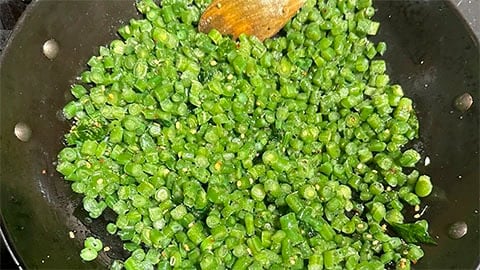 Chopped green beans added to wok.