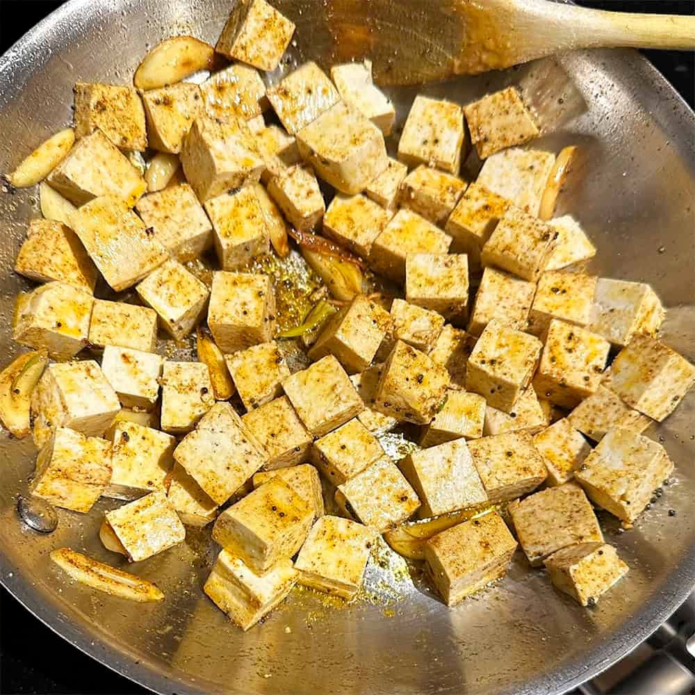 Tofu and garlic sauteing in oil with spices.
