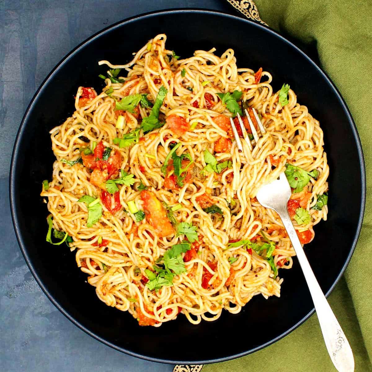 Top down view of chili garlic ramen noodles in black bowl with fork.