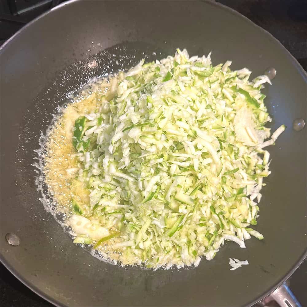 Grated mangoes added to wok.