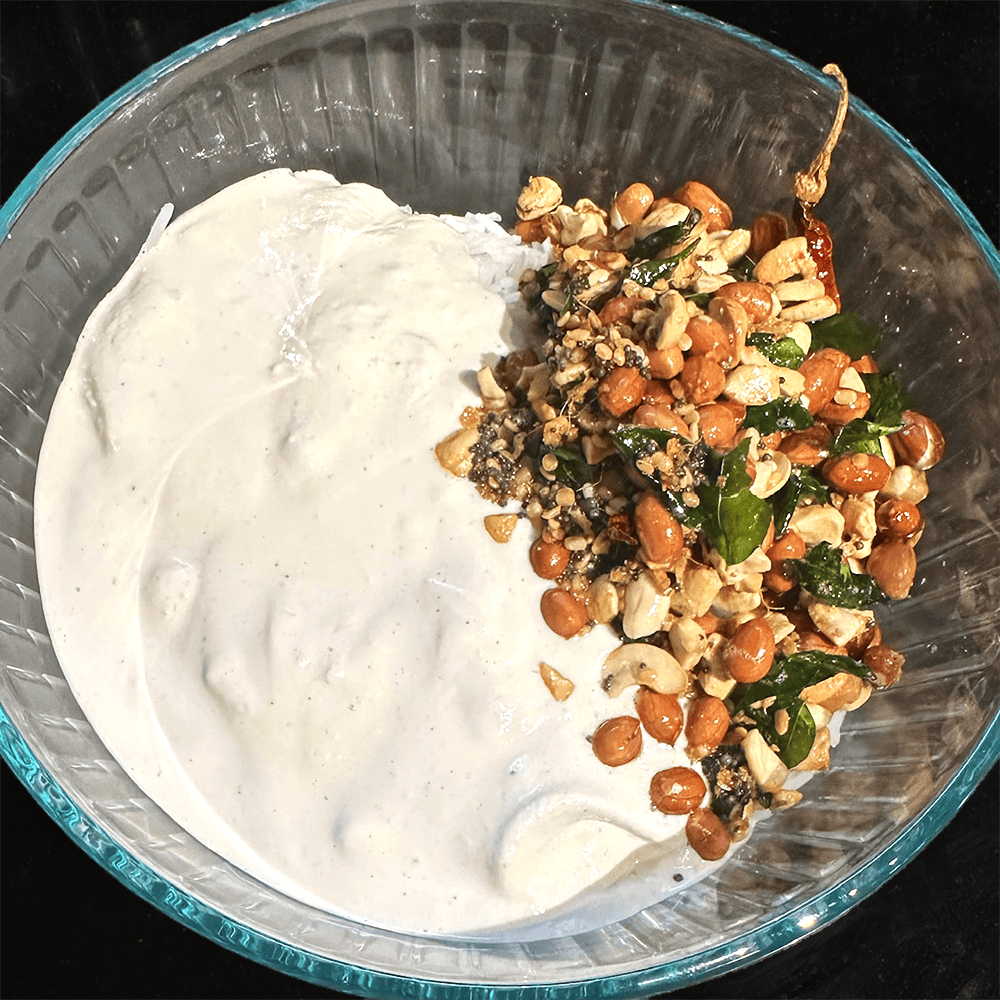 Tempering ingredients added to bowl with rice and yogurt.