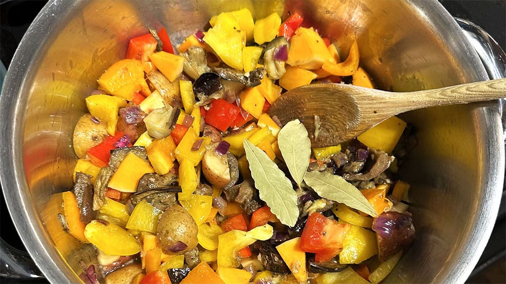 Vegetables for soufiko just tenderized and bay leaves added to pot.