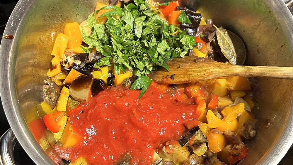 Tomatoes and fresh herbs added to pot.