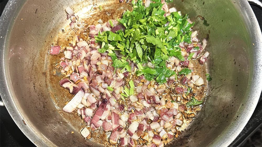 Onions and cilantro sauteing in pan.