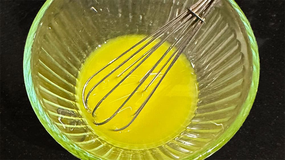 Olive oil and vinegar emulsified with a whisk in bowl.