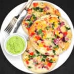 Uttapam on a plate with coconut chutney.