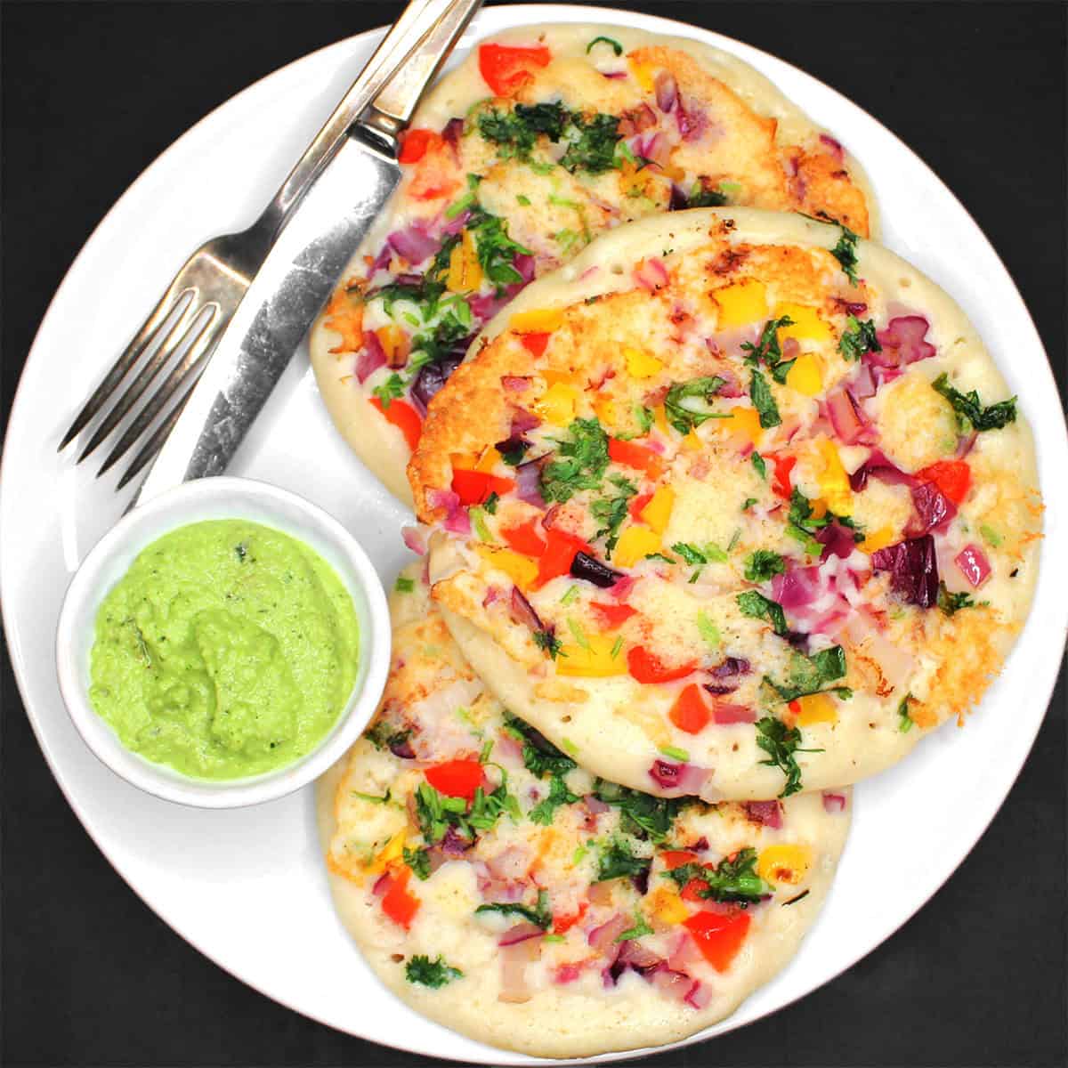 South Indian uttapam on a plate with coconut chutney.