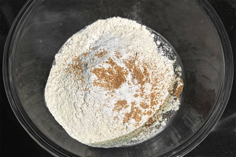 Flour, baking soda, baking powder and nutmeg in bowl.