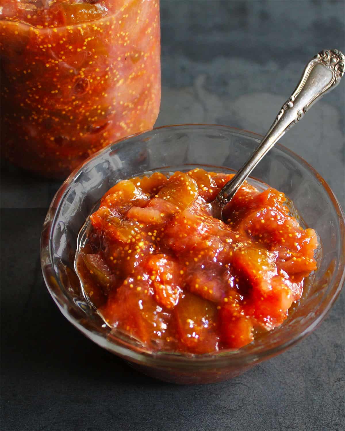 Fig jam in bowl and jar with fig jam in background.