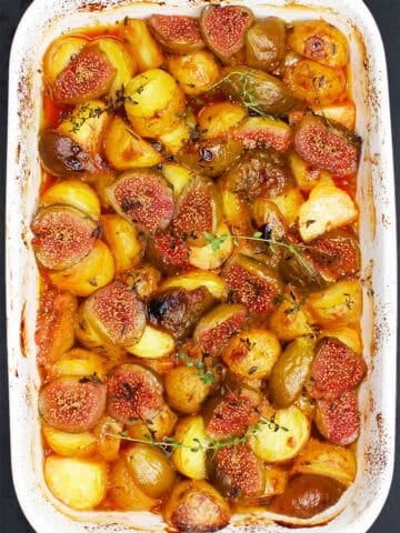Mediterranean baked figs and potatoes with thyme in white baking dish.