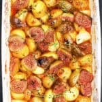 Overhead, close-up shot of Mediterranean-style roasted figs and potatoes in a white baking dish.