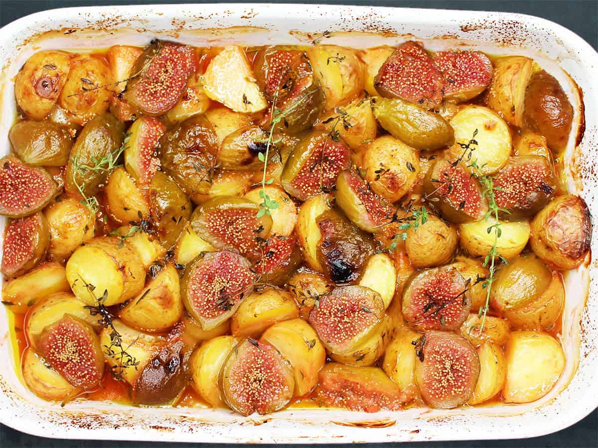 Overhead closeup view of Mediterranean-style oven-roasted figs and potatoes in a white baking dish.